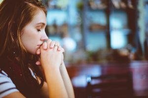 negative thinking woman resting chin on hands closing eyes