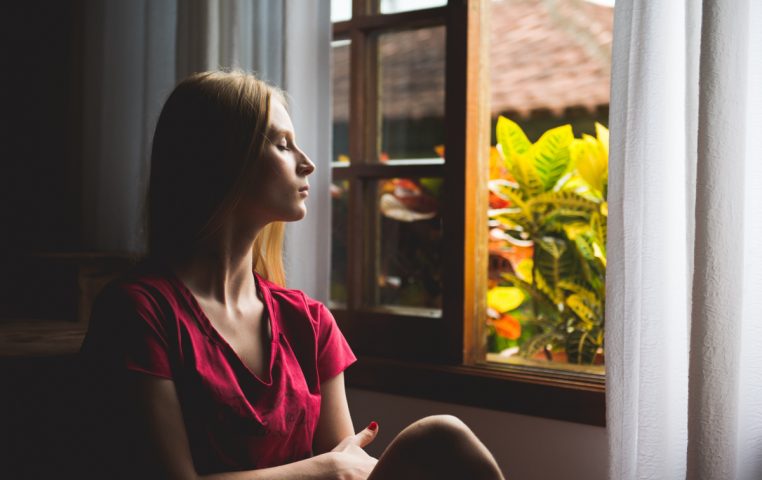 Woman sitting by window being more mindful